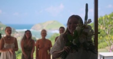 Elinde bir buket çiçek olan bir gelinin portresi ve onu arkasında duran nedimelerine atmak üzere. Düğün gelenekleri. Açık hava yaz töreni.