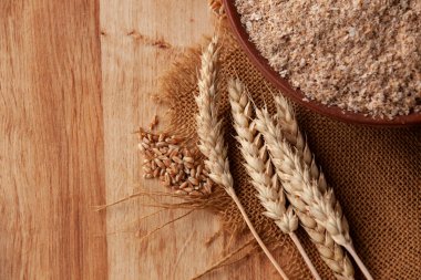 Kil kasede buğday kepeği ve ahşap arka planda buğday kulağı. Sağlıklı yemek geçmişi. Yemek ve pişirme malzemeleri. Boşluğu kopyala.