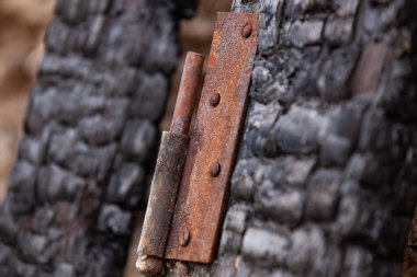 Yangından sonra kömürleşmiş ahşabın arka planında metalik bir ayrıntı var. Yangının sonuçları. Kapatın. Seçici odak.