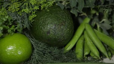Yeşil karışım. Bol miktarda yeşil sebze ve meyve hasadı: mikroyeşiller, yeşil soğanlar, bezelyeler, maydanoz, dereotu, avokado, limon, kabak ve sarı kabak. Döndürme atışı. Sağlıklı beslenme kavramı.