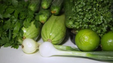 Yeşil karışım. Bol miktarda yeşil sebze ve meyve hasadı: mikroyeşiller, yeşil soğanlar, bezelyeler, maydanoz, dereotu, avokado, limon, kabak ve sarı kabak. Döndürme atışı. Sağlıklı beslenme kavramı.