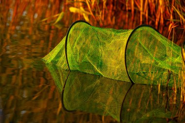 Fishing net amidst the reflections of sunset, perfect for themes of fishing, nature, and outdoor hobbies. Horizontal photo, close-up. clipart