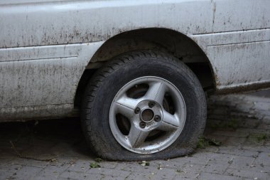 Lastiği patlamış kirli bir araba tekerleği, kullanılmadığını gösteriyor. Yatay fotoğraf.