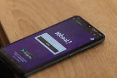 Kahoot 'u gösteren akıllı telefon ekranının yakın çekimi! Ahşap bir yüzeyde uygulama.