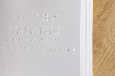 Bir kitabın kabartma yazıları. Tahta bir yüzeye yerleştirilmiş Braille yazılarının yakın görüntüsü. Erişilebilirlik temaları ve eğitim kavramları.