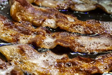 Siyah bir tavada pişen taze pastırma dilimleri. Yüksek kalite fotoğraf