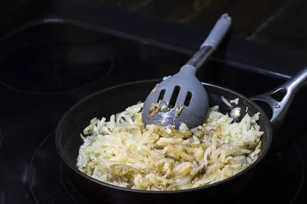キャストアイアンフライパンで調理するシュレッドハッシュブラウン 高品質の写真 — ストック写真
