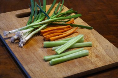 Tahta zemin üzerinde dilimlenmiş havuç yeşil soğan ve kereviz. Yüksek kalite fotoğraf