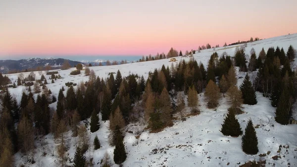 İHA ile İtalya 'daki Lancia grubunun hava görüntüsü. Kışın ortasında biraz kar ve arka planda tamamen izole edilmiş küçük bir kulübe var. Alacakaranlıkta gökyüzü kırmızı ve mavi renkte.