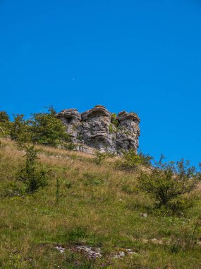 Tepedeki kaya oluşumunun arka planında mavi gökyüzü 