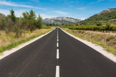 Boş asfalt yolu dağlara doğru gidiyor.