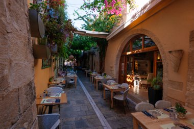 Yunanistan 'ın Rethymno kentindeki kasvetli boş sokak tavernası geleneksel konutları ve pembe bougainvillea çiçekleriyle