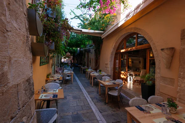 Yunanistan 'ın Rethymno kentindeki kasvetli boş sokak tavernası geleneksel konutları ve pembe bougainvillea çiçekleriyle