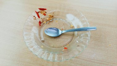 Masanın üzerinde çatal ve kaşık olan kırmızı plastik bir tabak.