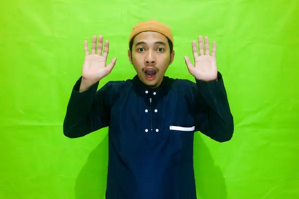 stock image Young Asian moslem man put hand near ear try to listening sound or secret news isolated on green background