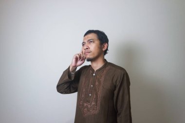 Müslüman Asyalı bir adam bir şey düşünürken ciddi bir ifade takınır.