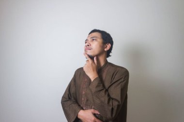 Müslüman Asyalı bir adam bir şey düşünürken ciddi bir ifade takınır.