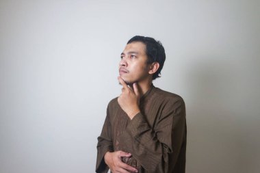 Müslüman Asyalı bir adam bir şey düşünürken ciddi bir ifade takınır.