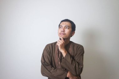 Müslüman Asyalı bir adam bir şey düşünürken ciddi bir ifade takınır.