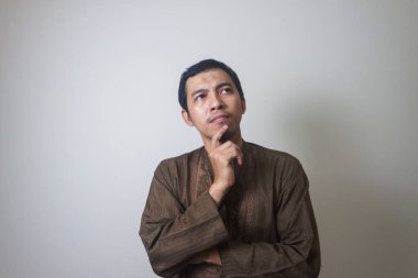 Müslüman Asyalı bir adam bir şey düşünürken ciddi bir ifade takınır.