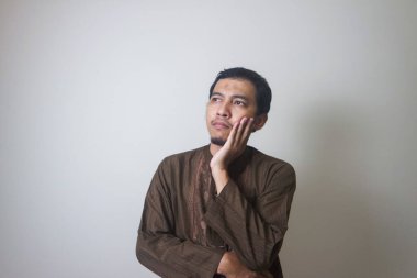 Müslüman Asyalı bir adam bir şey düşünürken ciddi bir ifade takınır.