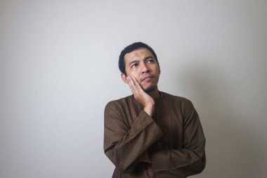 Müslüman Asyalı bir adam bir şey düşünürken ciddi bir ifade takınır.