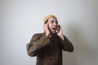 Dindar Müslüman adam, beyaz arka planda izole edilmiş Azan ya da İqamah 'ı okuyor.