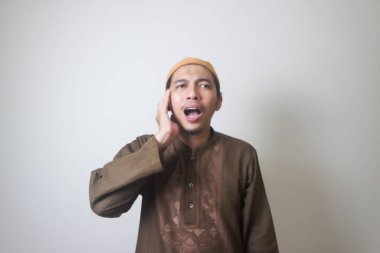 Dindar Müslüman adam, beyaz arka planda izole edilmiş Azan ya da İqamah 'ı okuyor.