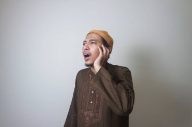 Dindar Müslüman adam, beyaz arka planda izole edilmiş Azan ya da İqamah 'ı okuyor.