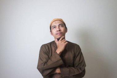 Müslüman Asyalı bir adam bir şey düşünürken ciddi bir ifade takınır.