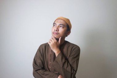 Müslüman Asyalı bir adam bir şey düşünürken ciddi bir ifade takınır.