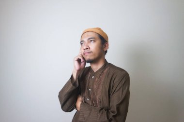 Müslüman Asyalı bir adam bir şey düşünürken ciddi bir ifade takınır.
