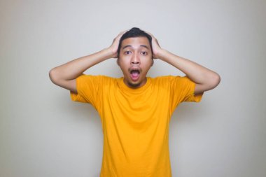 Beyaz arka planda poz veren Asyalı genç bir adamın portresi