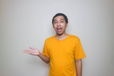 Heyecanlı Asyalı adamın harika bir fikri var ve beyaz arka planda izole edilmiş bir yeri işaret ediyor.