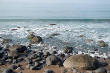 Deniz dalgası sahilde yosunlu kayalara çarpıyor. Güzel ve sakin sahil atmosferi