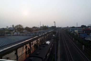 Railway with electrical cable for commuter line surrounding by trees and bushes at Depok Station photo taken in Depok Indonesia clipart