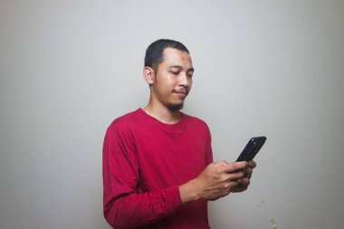 Smart casual asian man using smartphone in studio background