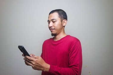 Smart casual asian man using smartphone in studio background