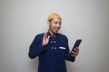 Beyaz arka planda izole edilmiş cep telefonu kullanan Asyalı Müslüman.