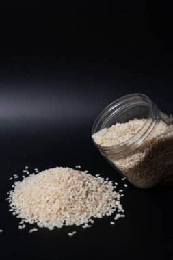 Siyah susam tohumlarının en üst görüntüsü ve arka planda tahta bir kaşık. Temiz kompozisyon yemek blogları, sağlıklı gıda içeriği veya baharatla ilgili ürünler için idealdir. Doğal dokuyu ve renk karşıtlığını vurgular.