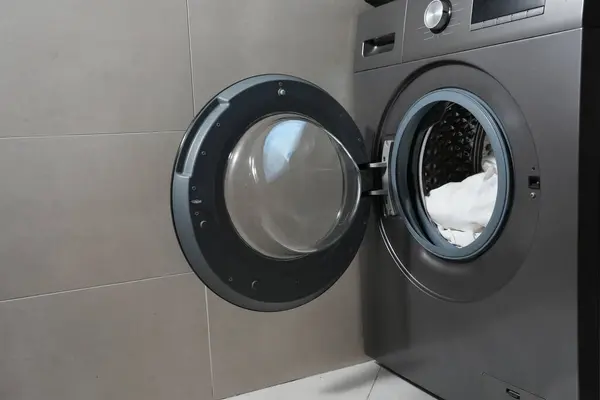 Modern bir çamaşır makinesinde programın seçici kadranını çeviren bir elin yakın çekimi. Çamaşır yıkama modu, günlük rutin veya ev aletleri kullanımı kavramı.