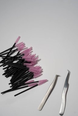 Kirpik uzatma aletleri koleksiyonu, beyaz bir arkaplanda düzenlenmiş fırçalar, cımbızlar ve göz bantları, kirpik sanatçıları ve güzellik uzmanları için mükemmel..