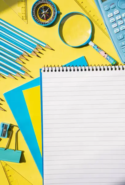  Sarı yüzeydeki sarmal not defteri ve kırtasiye malzemesi. Eğitim, öğrenim ve okul kavramları için parlak yaratıcı çalışma alanı. 