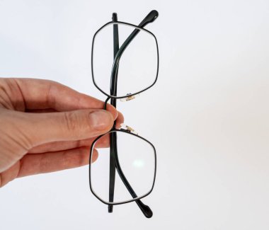 Beyaz arka planda modern gözlüklerle el ele tutuşmak. Bakım, sağlık, okuma gözlüğü, optik hizmet ve minimum yaşam tarzı kavramı. 