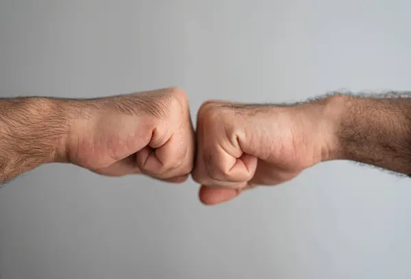 Yumruk tokuşturma hareketi yapan erkek eller. Güven, iş başarısı ve karşılıklı desteğin sembolü. 