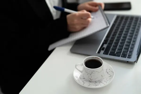 Yanında mermer fincan kahve ve çerçevesinde dizüstü bilgisayarı olan bir not defterine el yazısı yakın plan. Strateji ve görsel çalışmalar için harika.. 