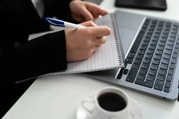 Dizüstü bilgisayar ve fincanın yanında sıkı bir yazı var. Takım elbise içeriği planlaması, çalışma, metin yazımı ve üretkenlik içeriği. 