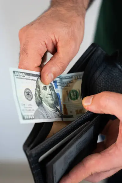 Hands holding wallet with US dollar bills partly visible. Concept of salary, income, financial planning, and business success. 