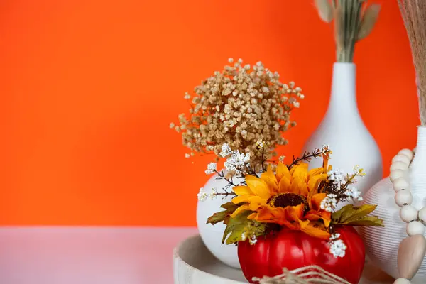 Beyaz vazoda turuncu arkaplanlı şenlikli sonbahar buketi. Şükran Günü için mükemmel mevsimlik dekorasyon..