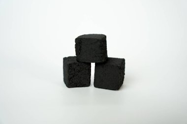 Temiz beyaz zemin üzerine istiflenmiş siyah shisha kömür küpleri, sigara içme, rahatlama, ateş ve yaşam tarzı kavramlarının sembolü. 